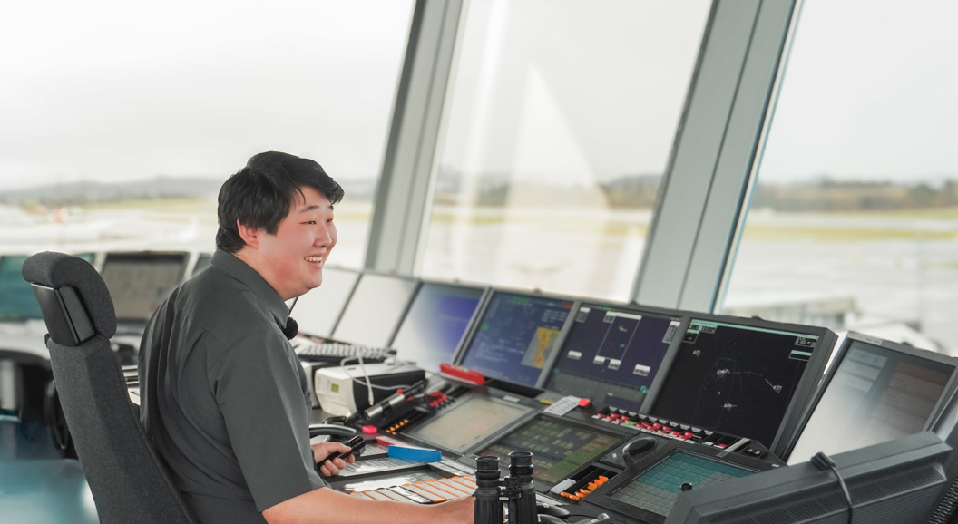 Flygeleiar i eit flykontrolltårn overvaker flytrafikken ved hjelp av kikkert og dataskjermer.