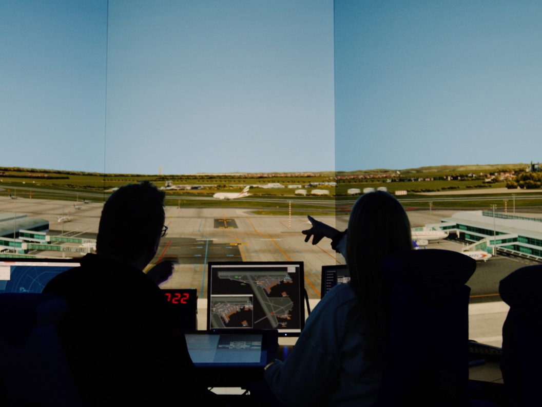 Kontrollrom på flyplass med personar som overvakar rullebanene frå skjermer