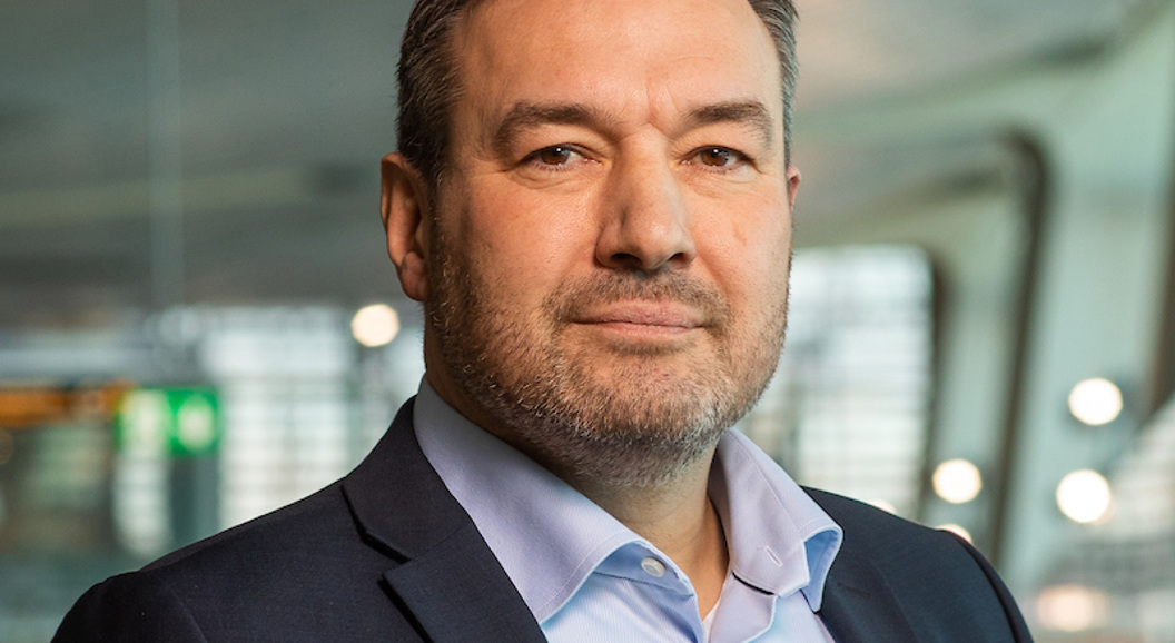 Mann i dress i moderne kontorlokale, ser direkte mot kamera.