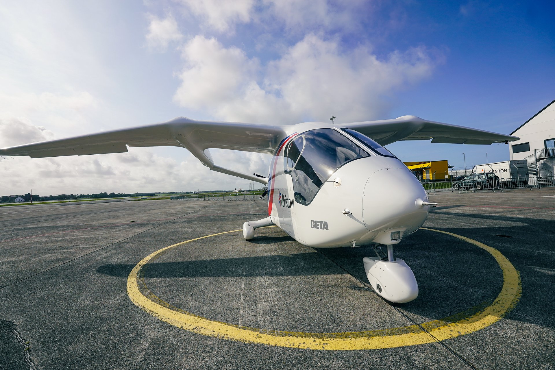 Electric aircraft on tarmac under blue sky, showcasing sustainable aviation technology at an airport.