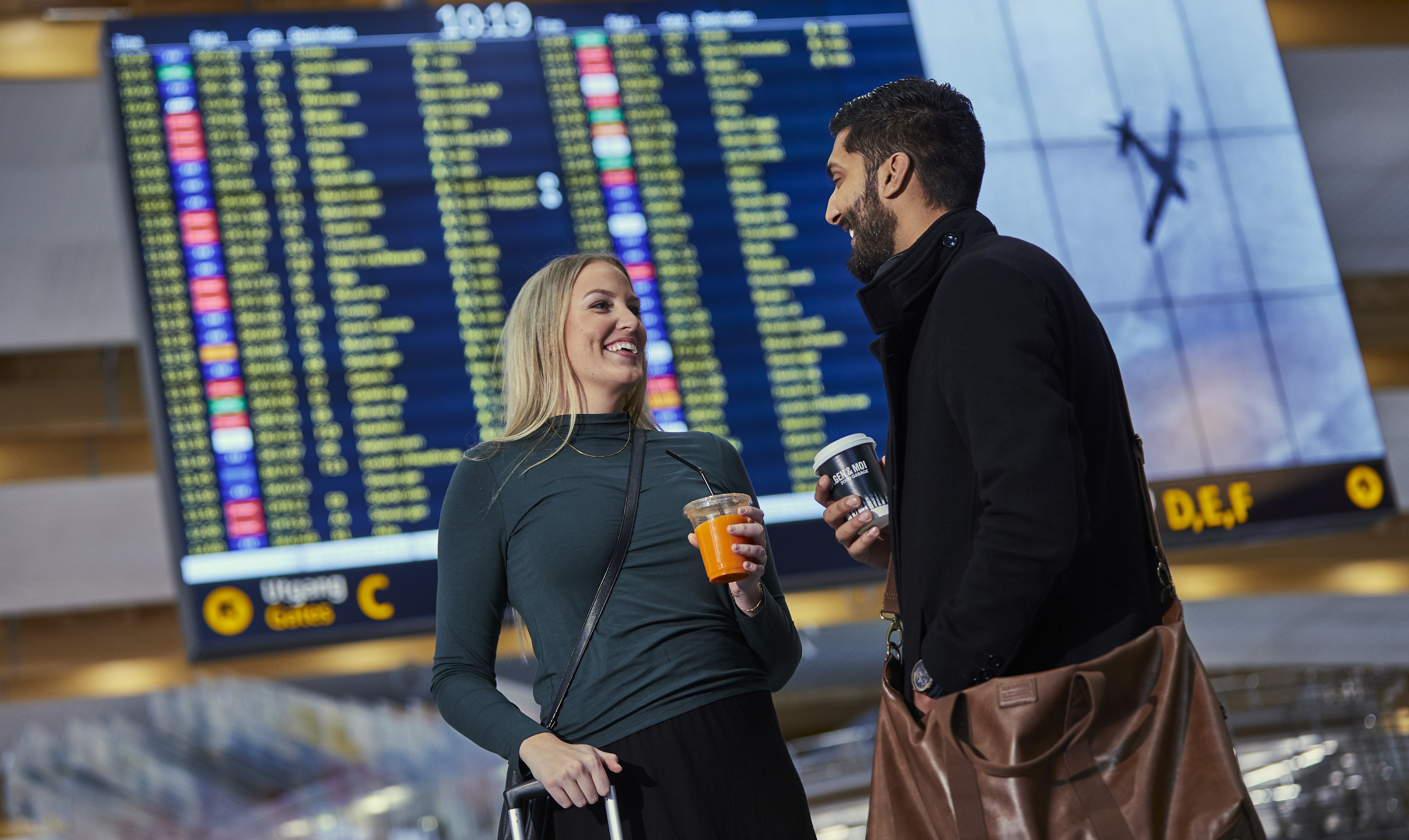 Mennesker foran en flyinformasjon skjerm
