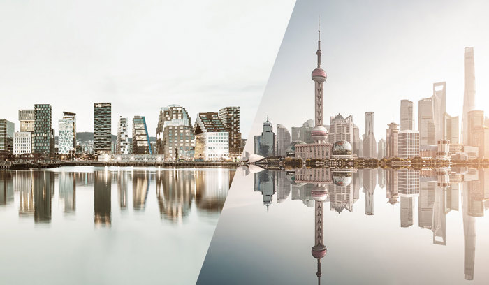 Panoramabilde av moderne bysilhuetter, delt mellom Oslos Barcode-prosjekt og Shanghais skyline, reflektert i vannet.