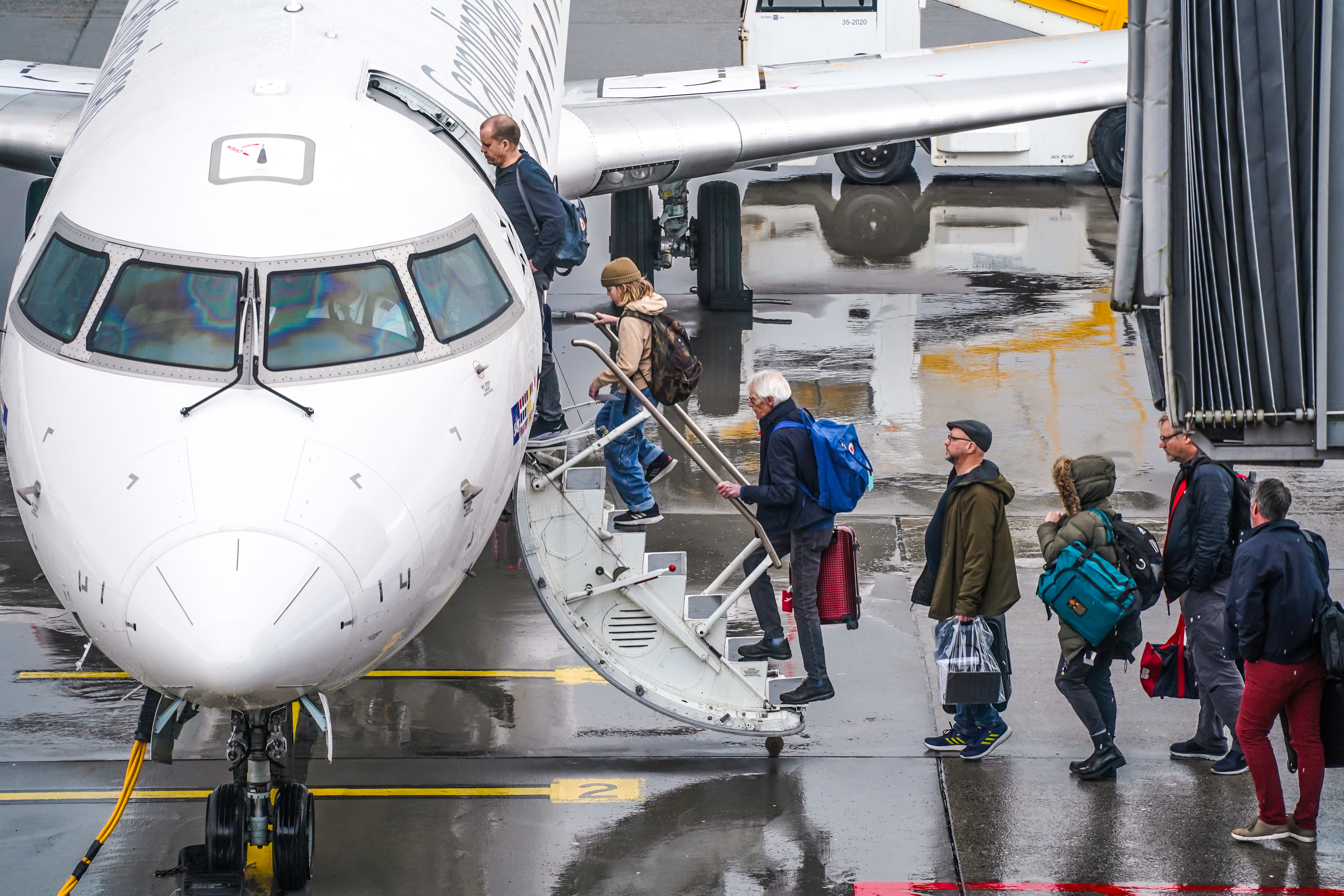 Passengers board a plane on a rainy day at the airport.