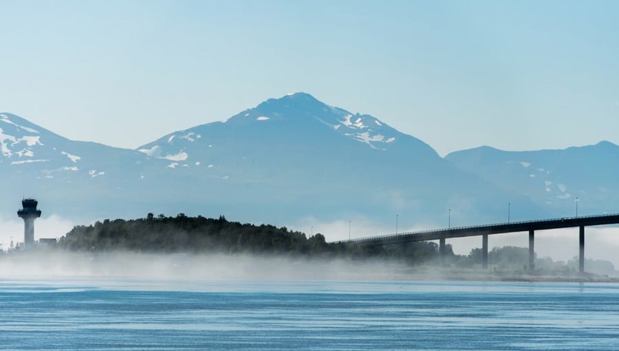 Bridge over water with mountains in the background near Ålesund, Norway, shrouded in mist.