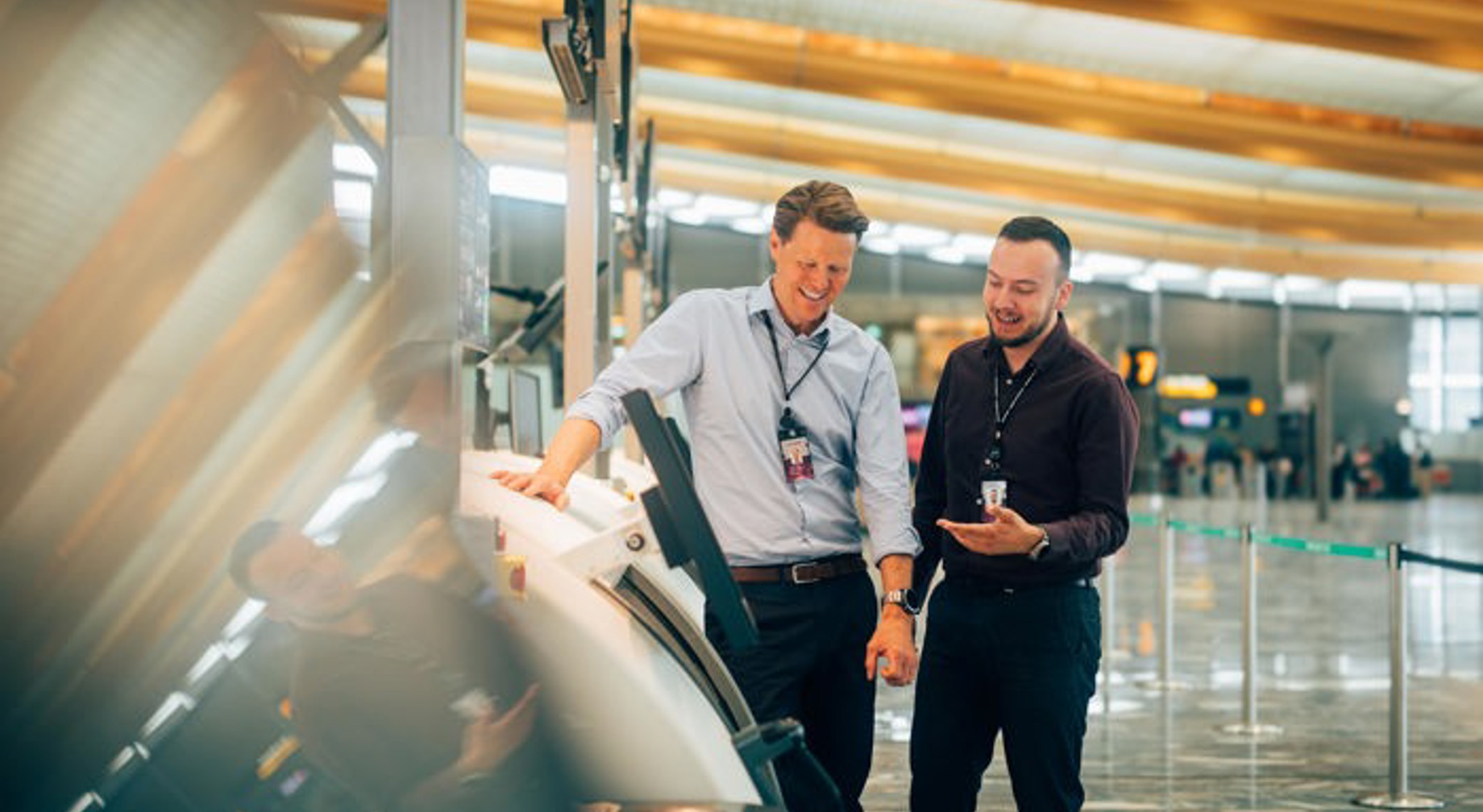 Woman points at screen in control room, smiles and looks focused. Screens with data in the background.