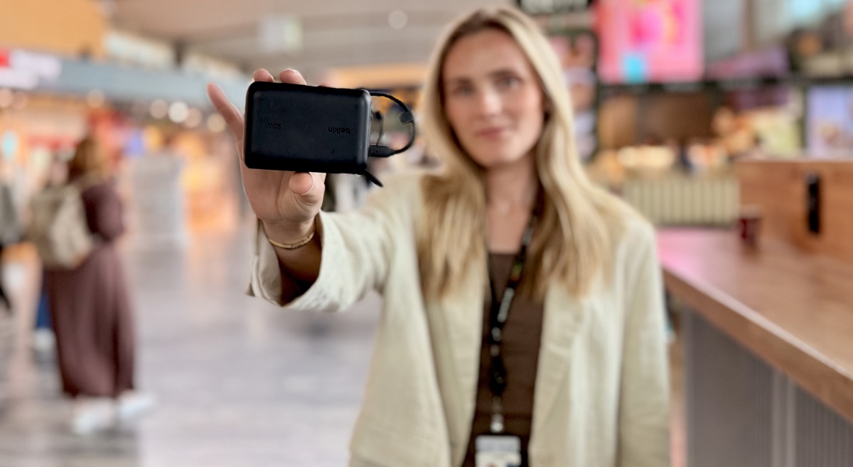Dame som holder en powerbank på flyplass.