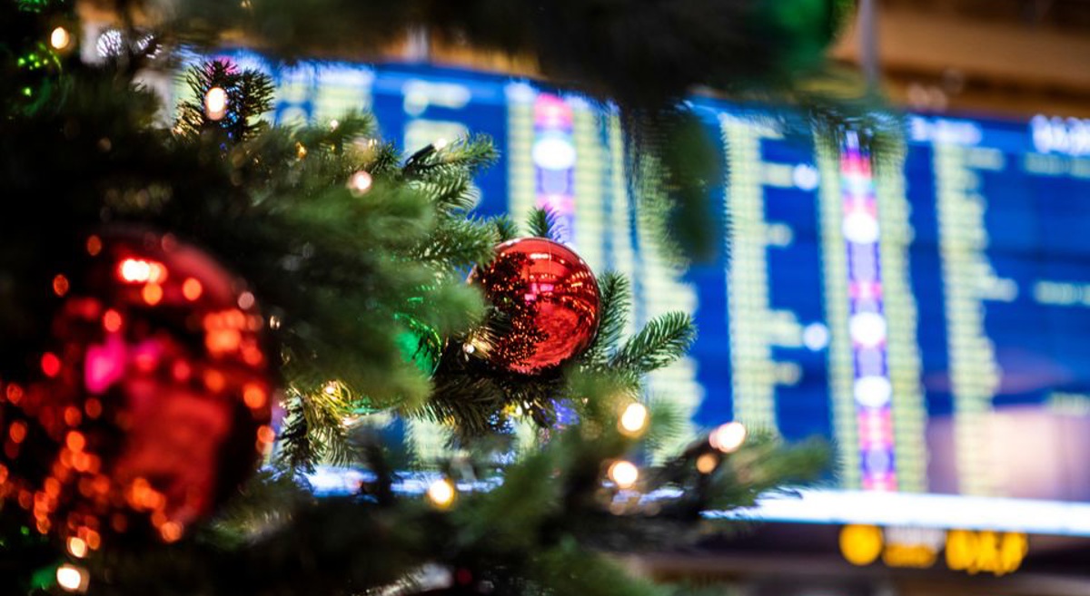 Juletrepynt med røde kuler foran informasjonstavle på flyplass, som illustrerer julefeiring under reiser