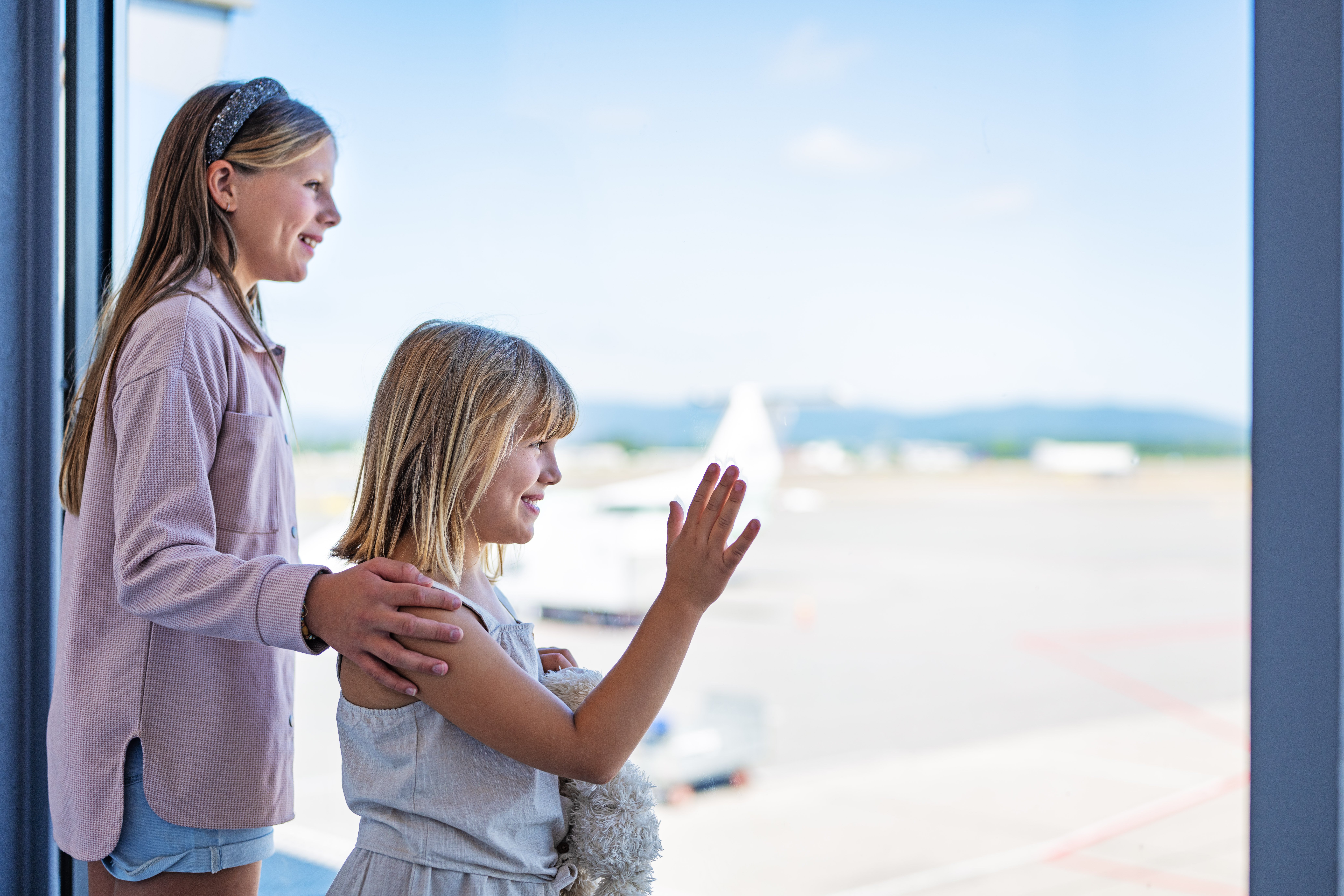 Children looking out a window at the airport