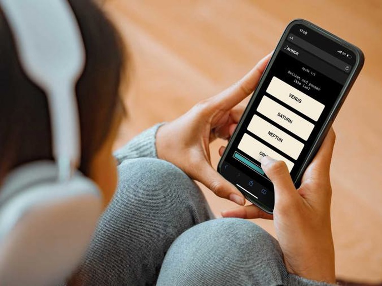 Person med hovudtelefonar held ein smarttelefon som viser ein quiz-app med spørsmål om planetar.