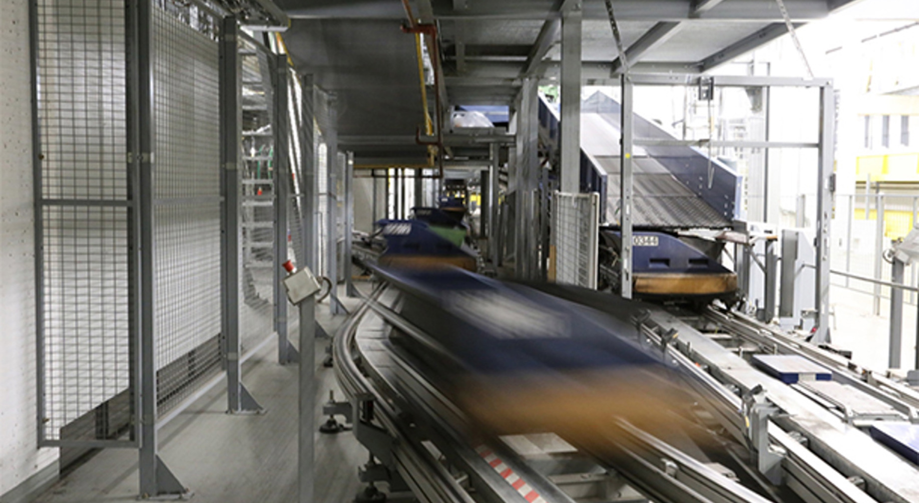 Sorteringssystem for bagasje på ein flyplass, med transportbånd og automatiserte vogner i ei industriell innstilling